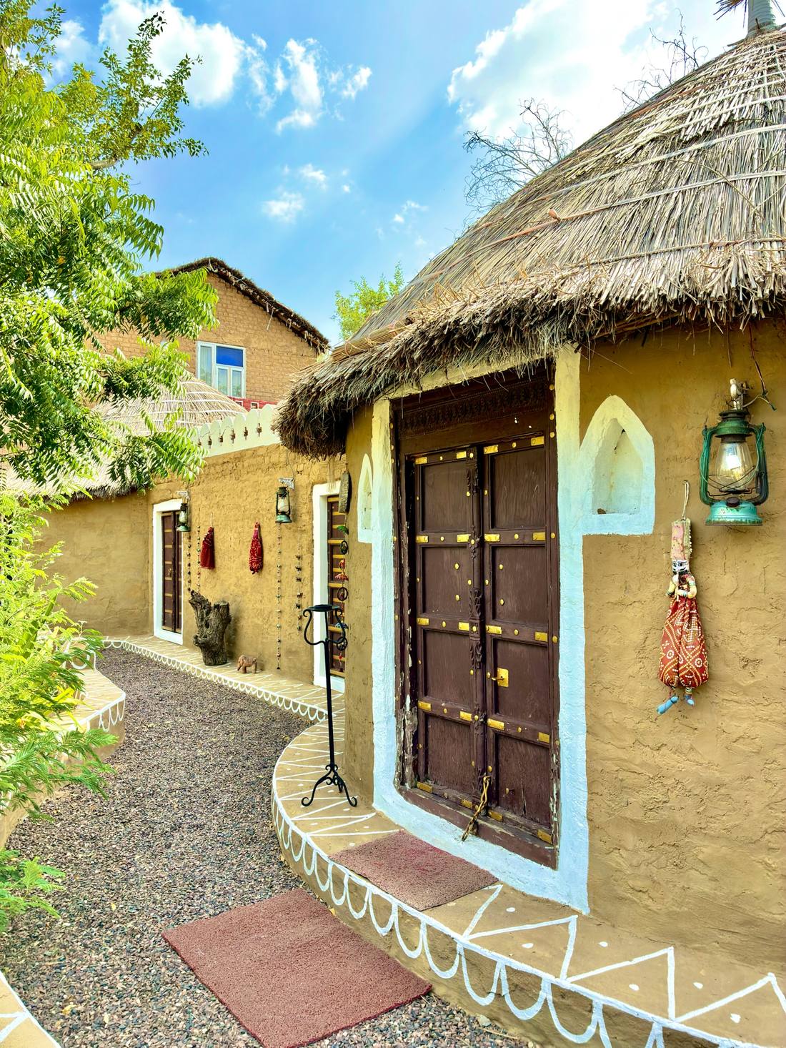 Thatched mud cottages and a lantern-lit path at Umaid Safaris